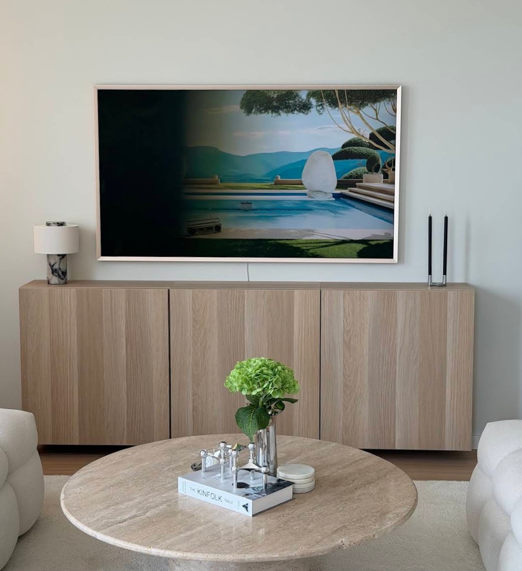 Väggmonterad TV ovanför en sideboard i trä i ett ljust vardagsrum – TV-montering av Hamitek i Stockholm