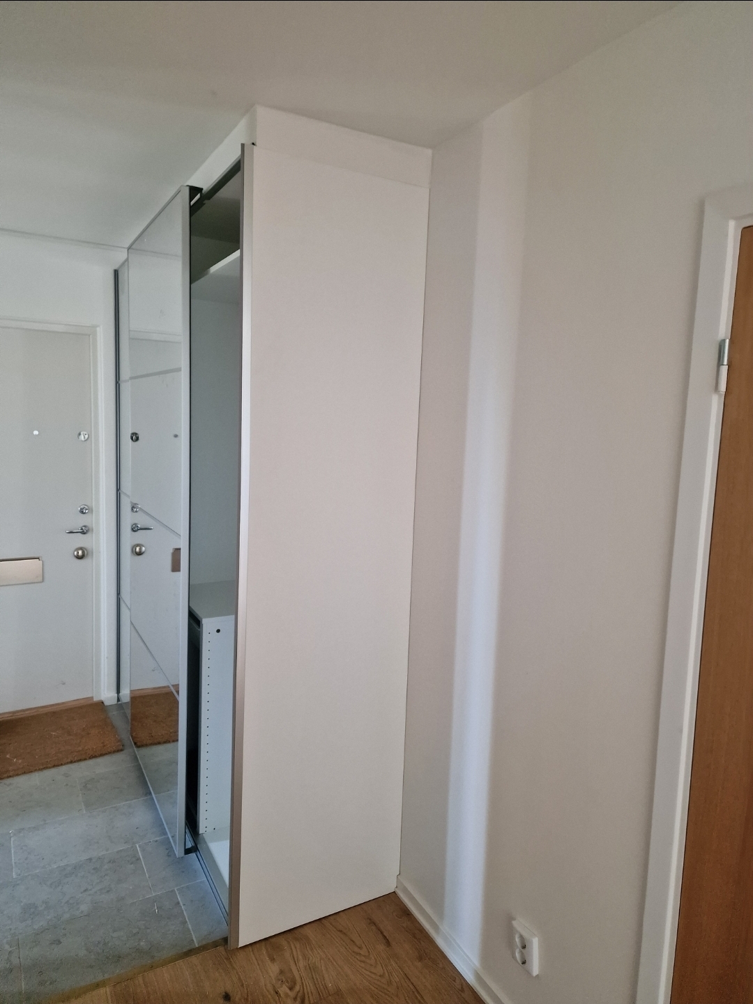 Måttanpassad garderob med skjutdörrar i spegel och platsbyggd sidopanel i hall – platsbyggd garderob av Hamitek i Stockholm